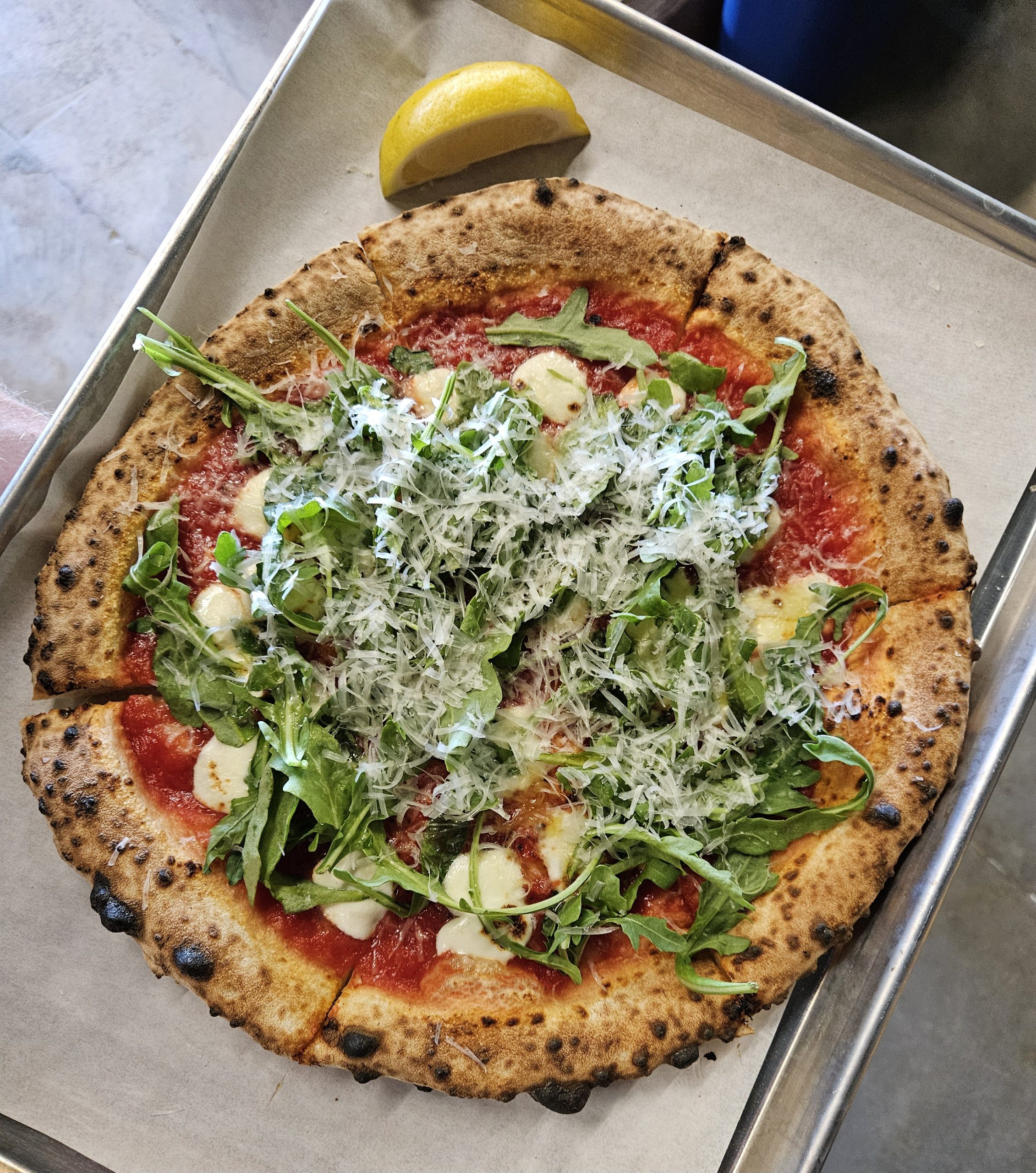 Arugula pizza with fresh arugula, parm, and lemon